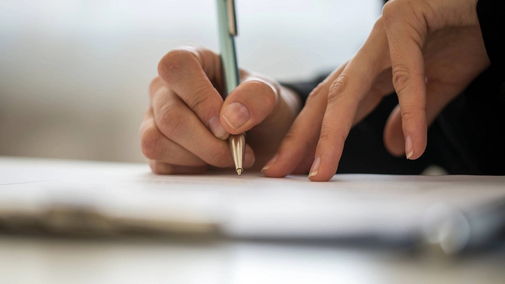 Jemand schreibt etwas auf ein Stück Papier.