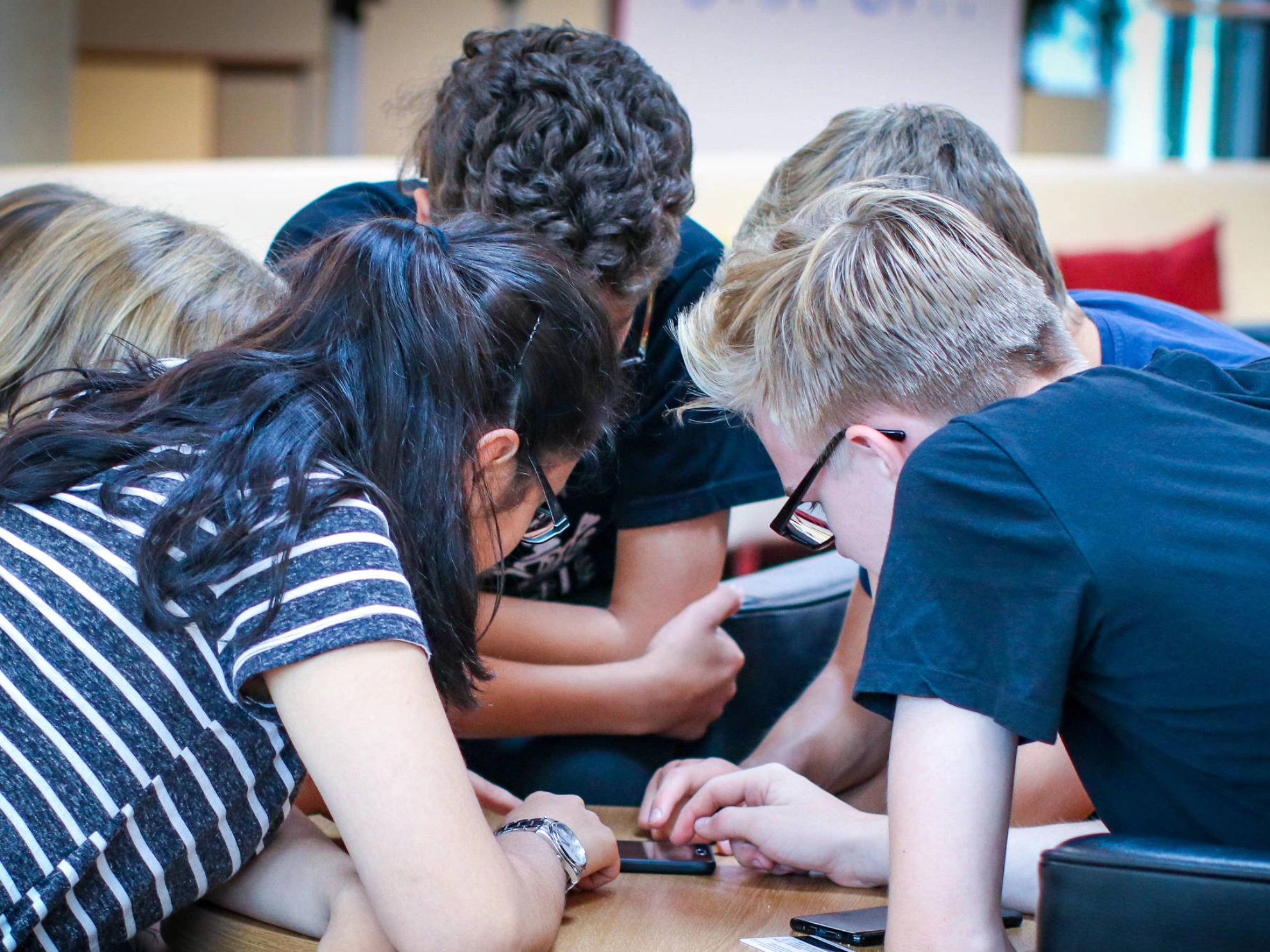 Eine Gruppe Jugendliche schaut gemeinsam in ein Handy.