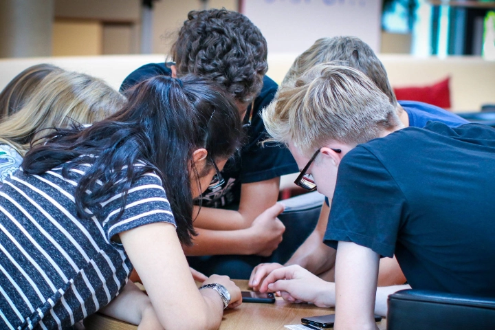 Eine Gruppe Jugendliche schaut gemeinsam in ein Handy.